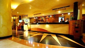 A hotel reception area with a marble floor, a reception desk, and a cashier counter. - Hotel Sentral Jakarta (Jakarta)