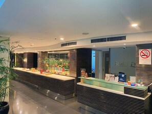 A reception area with a modern design, featuring a reception desk, a no-smoking sign, and a glass display case with items.