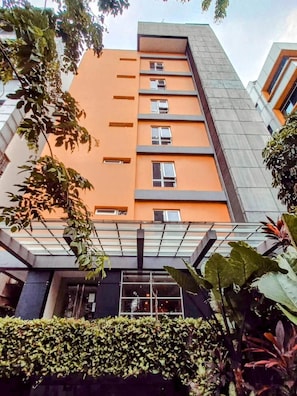Un edificio de varios pisos con un diseño arquitectónico moderno, que presenta un techo plano y una serie de ventanas en cada planta.