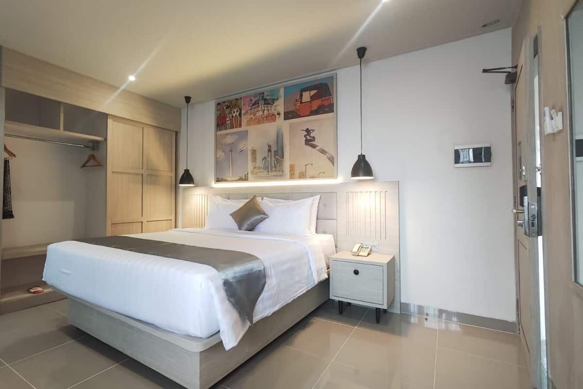 Ein modernes Hotelzimmer mit einem großen Bett, Nachttischen, einem Kleiderschrank und einem Bild an der Wand.