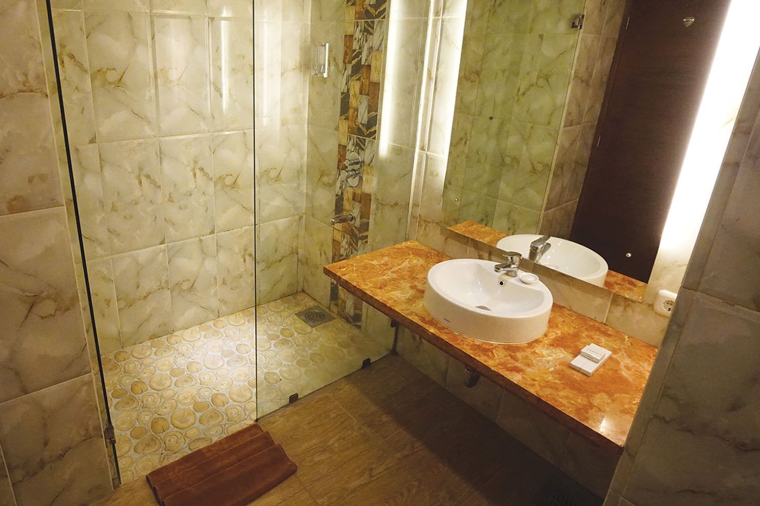Une salle de bain avec un sol en marbre, un lavabo avec un miroir et un espace douche.