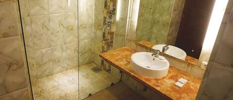 A bathroom with a marble floor, a sink with a mirror, and a shower area.