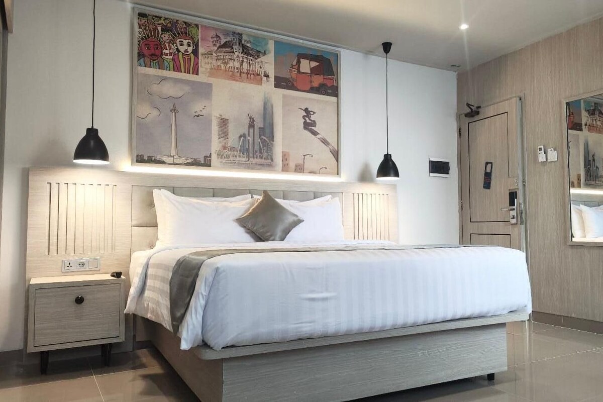 Un dormitorio moderno con cama, mesitas de noche, un espejo grande y obras de arte en la pared.