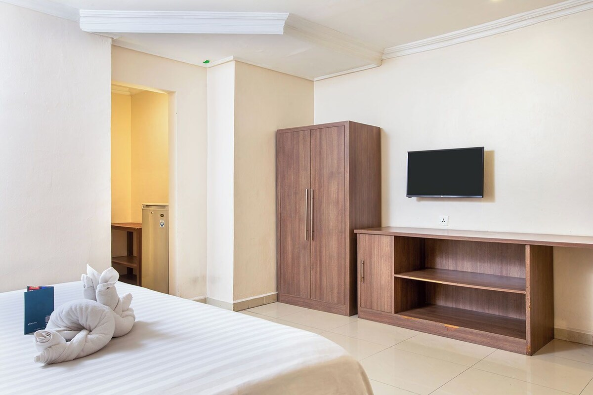 Ein Hotelzimmer mit Bett, Schrank, Fernseher und Schreibtisch.