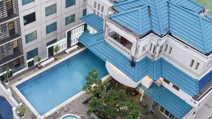 A rooftop pool with a blue roof, surrounded by potted plants and a small circular fountain. - 1O1 URBAN Jakarta Thamrin (Jakarta)