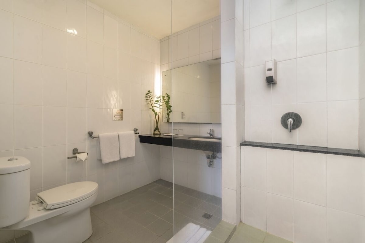 Une salle de bain moderne équipée de toilettes, d’un lavabo et d’un espace douche.