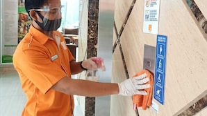 A person in an orange uniform cleaning a marble reception desk with a spray bottle and gloves. - V Hotel Tebet, Jakarta (Jakarta)