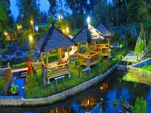 A serene garden with a pond, wooden gazebos, and well-maintained vegetation. - Grage Sangkan & Spa (WEST JAVA)