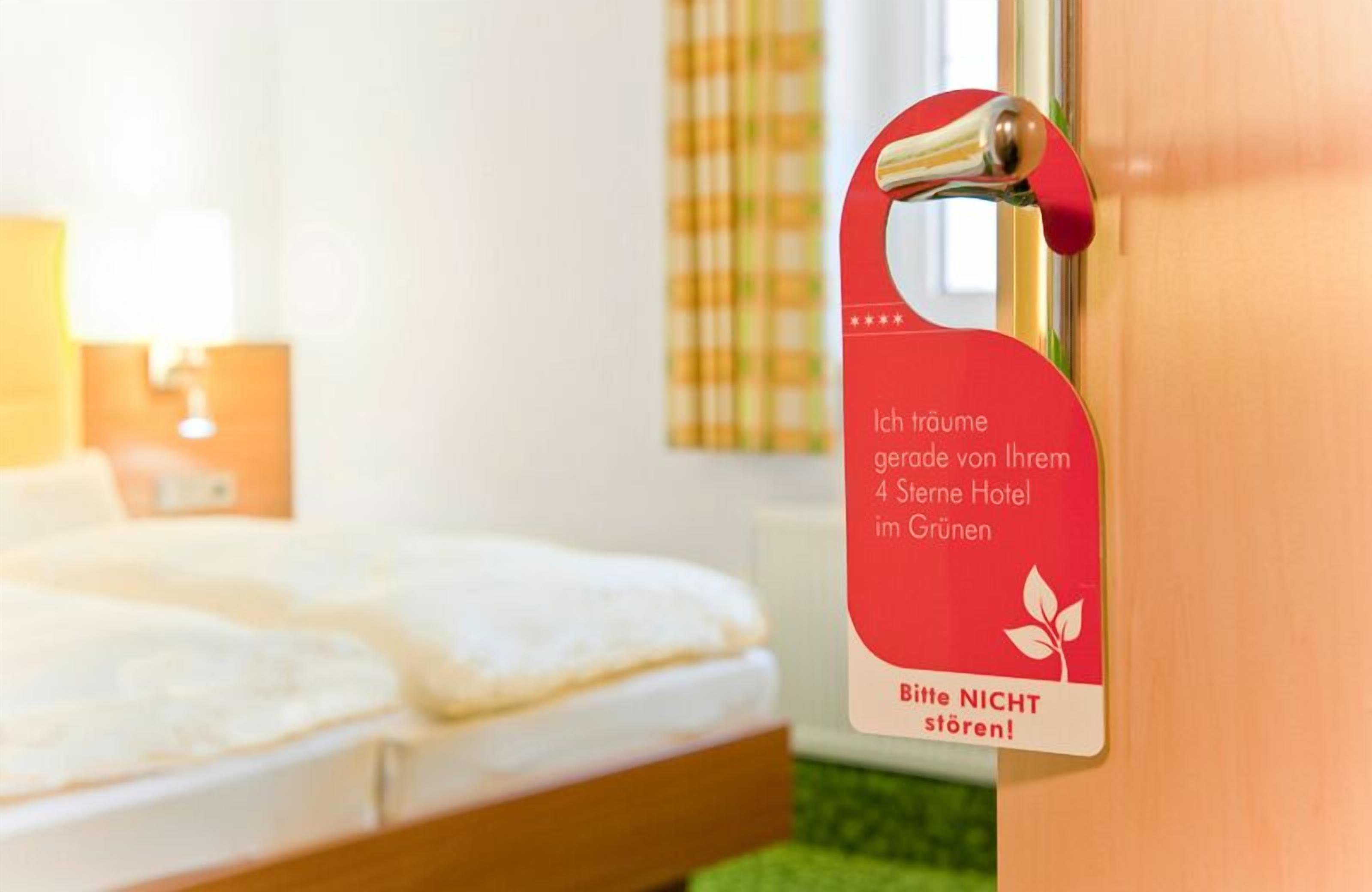 Ein Hotelzimmer mit Bett, Nachttisch und einem roten Schild an der Tür.