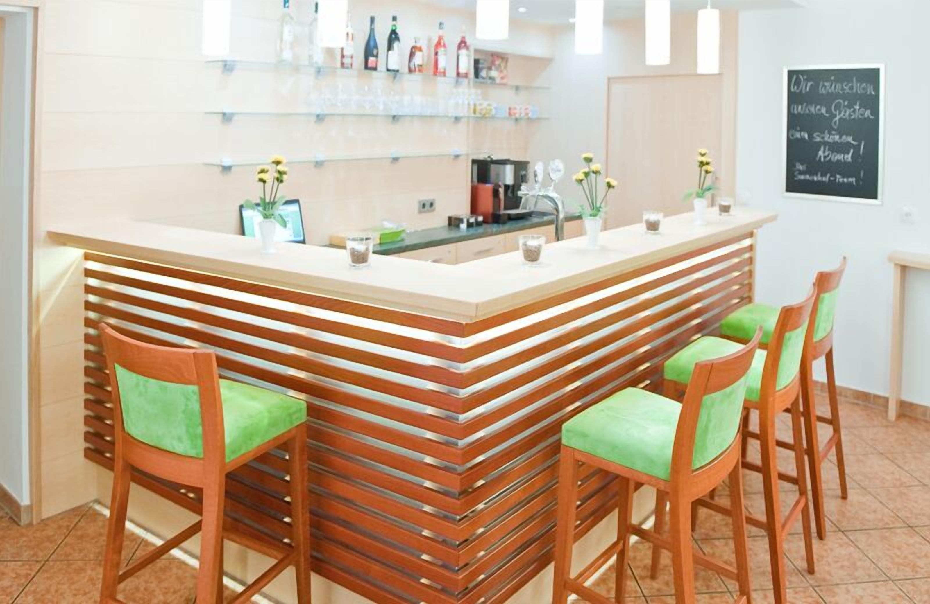 A reception area with a wooden counter, green cushioned chairs, and a wall-mounted display of items.