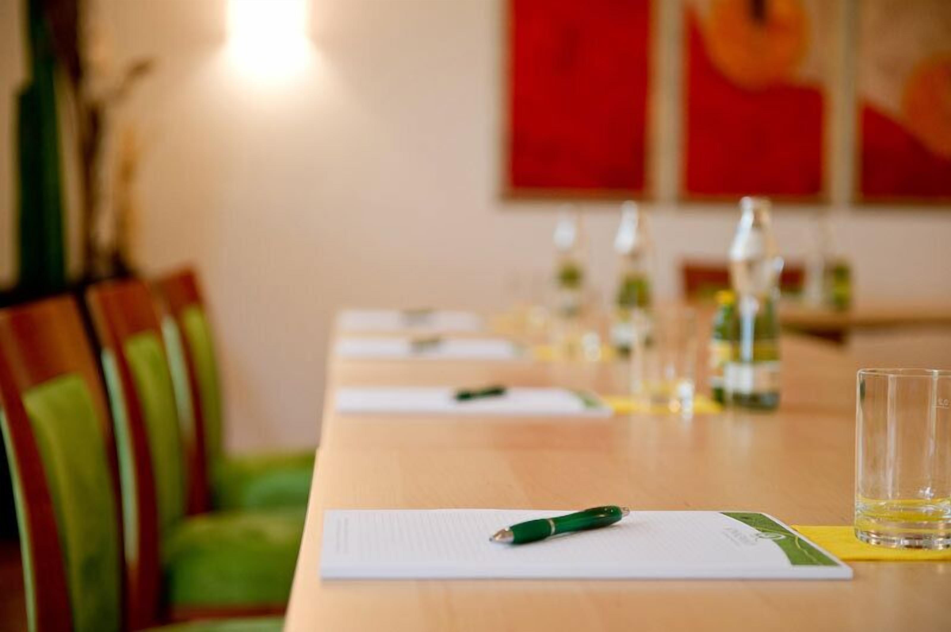 Una mesa de conferencias con documentos, bolígrafos y vasos de agua.