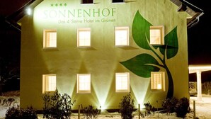 Un edificio con el nombre "SONNENHOF" y la inscripción "Das 4 Sterne Hotel im Grün" en su fachada.