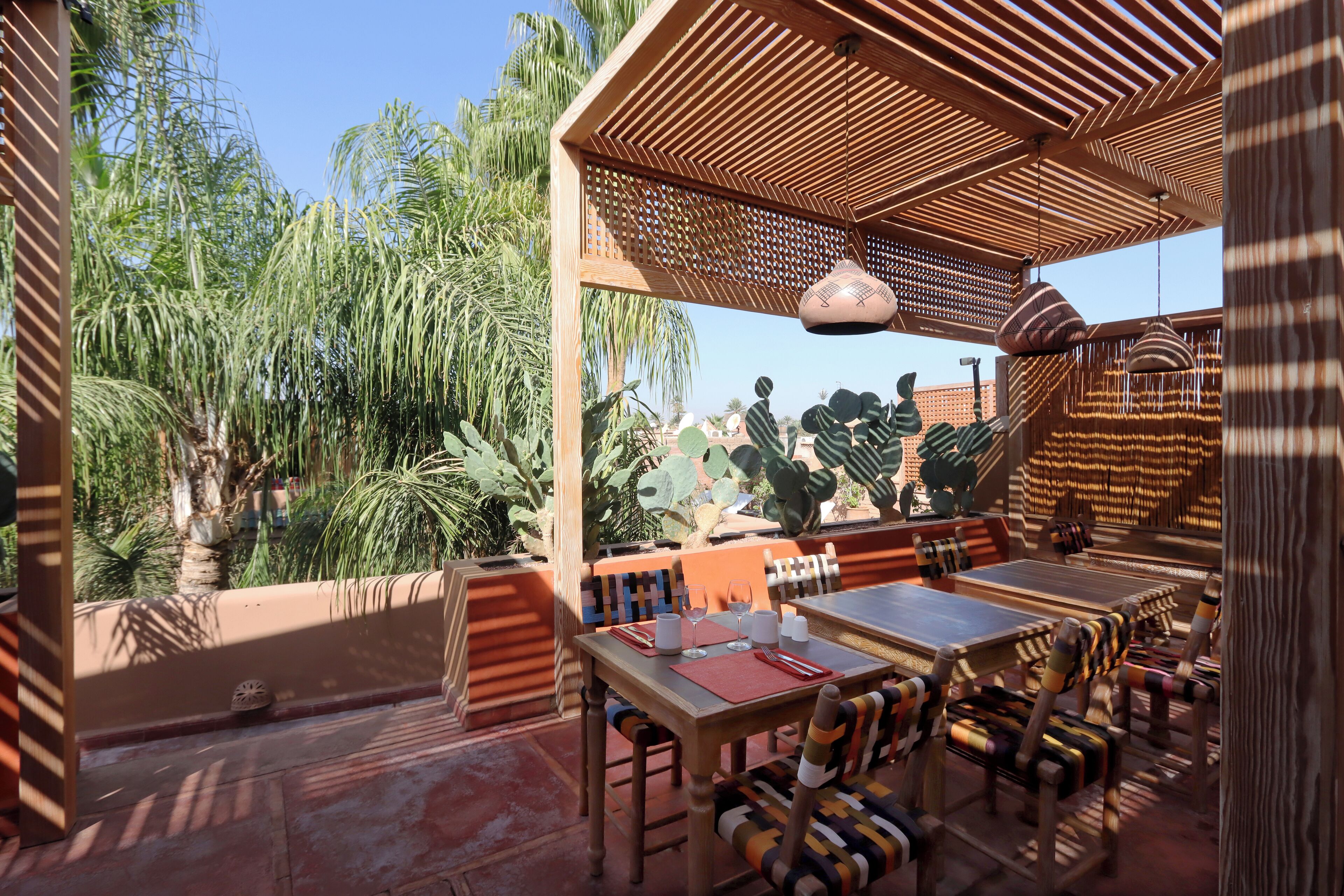 An outdoor dining area with wooden furniture and a view of tropical plants.