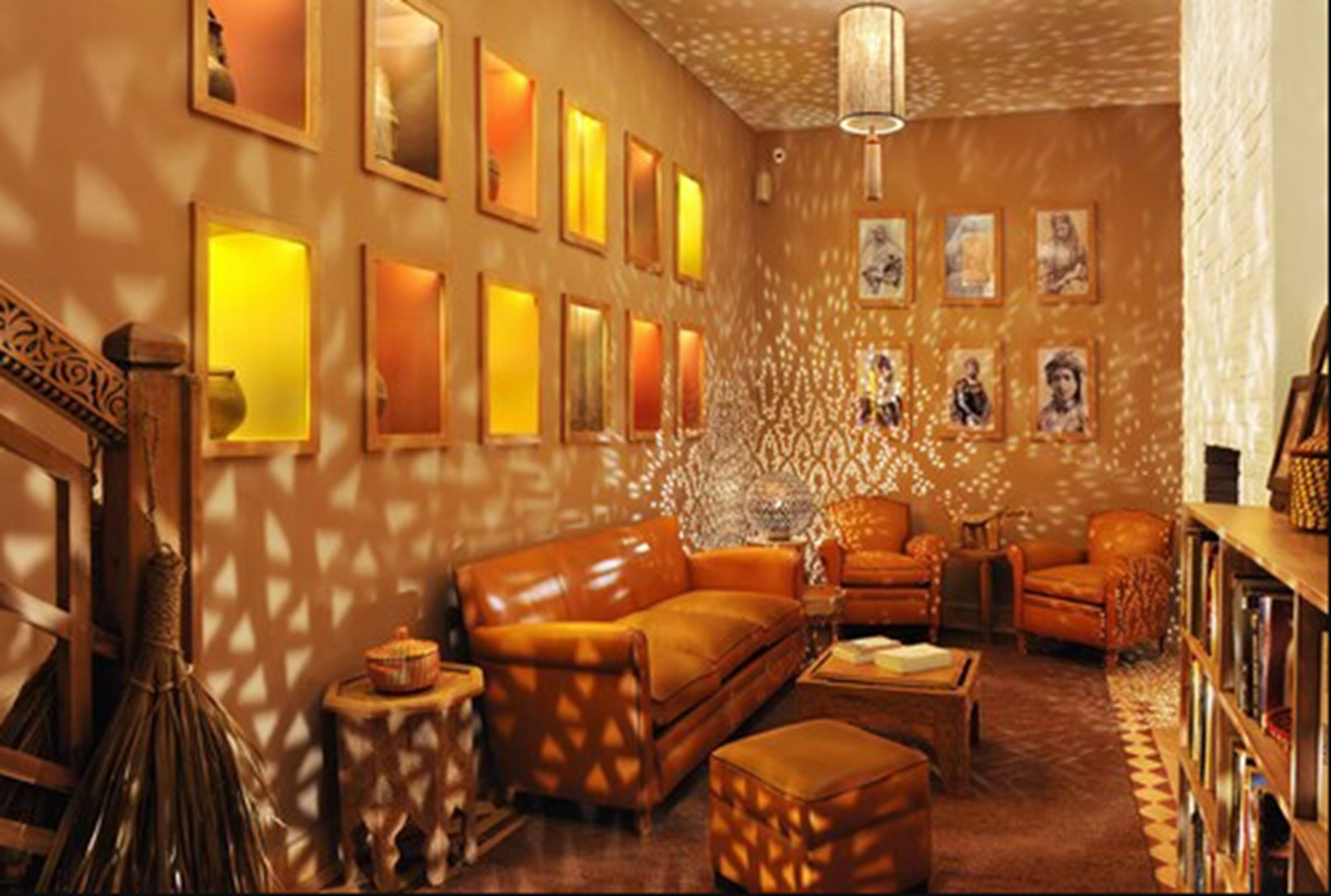 A cozy living room with a sofa, armchairs, and a coffee table. There are framed pictures on the wall and a chandelier.