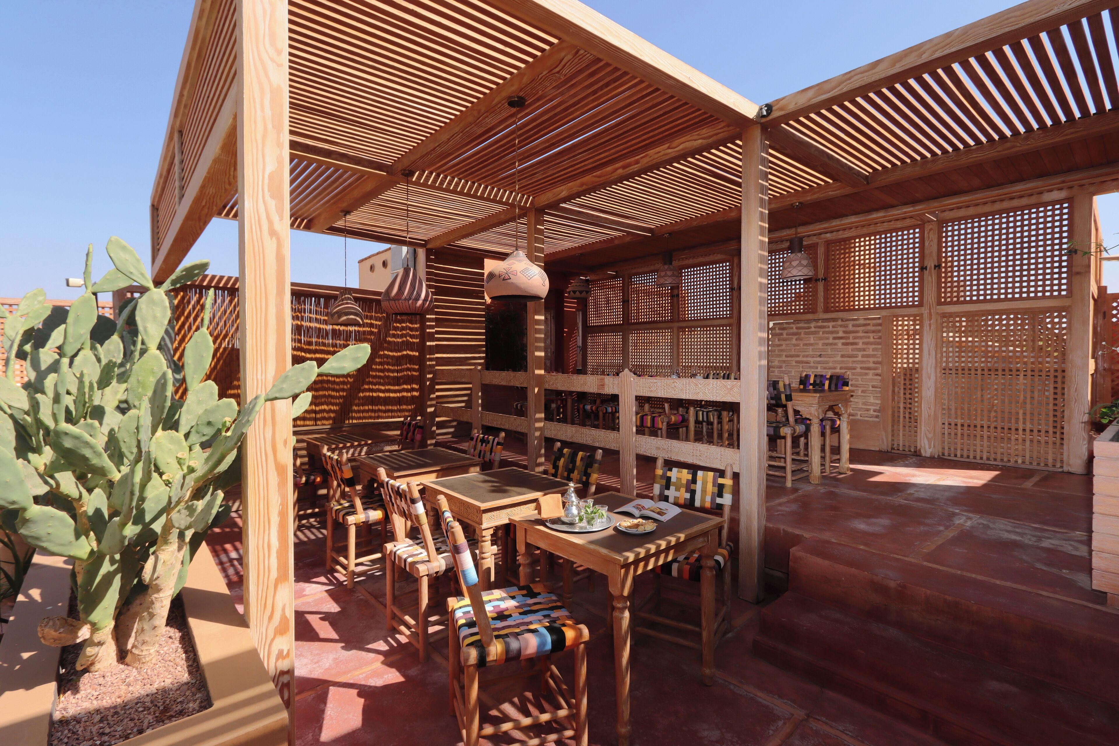 Ein Patio im Freien mit Holzmöbeln, einer Kakteepflanze und einem Backsteinboden.