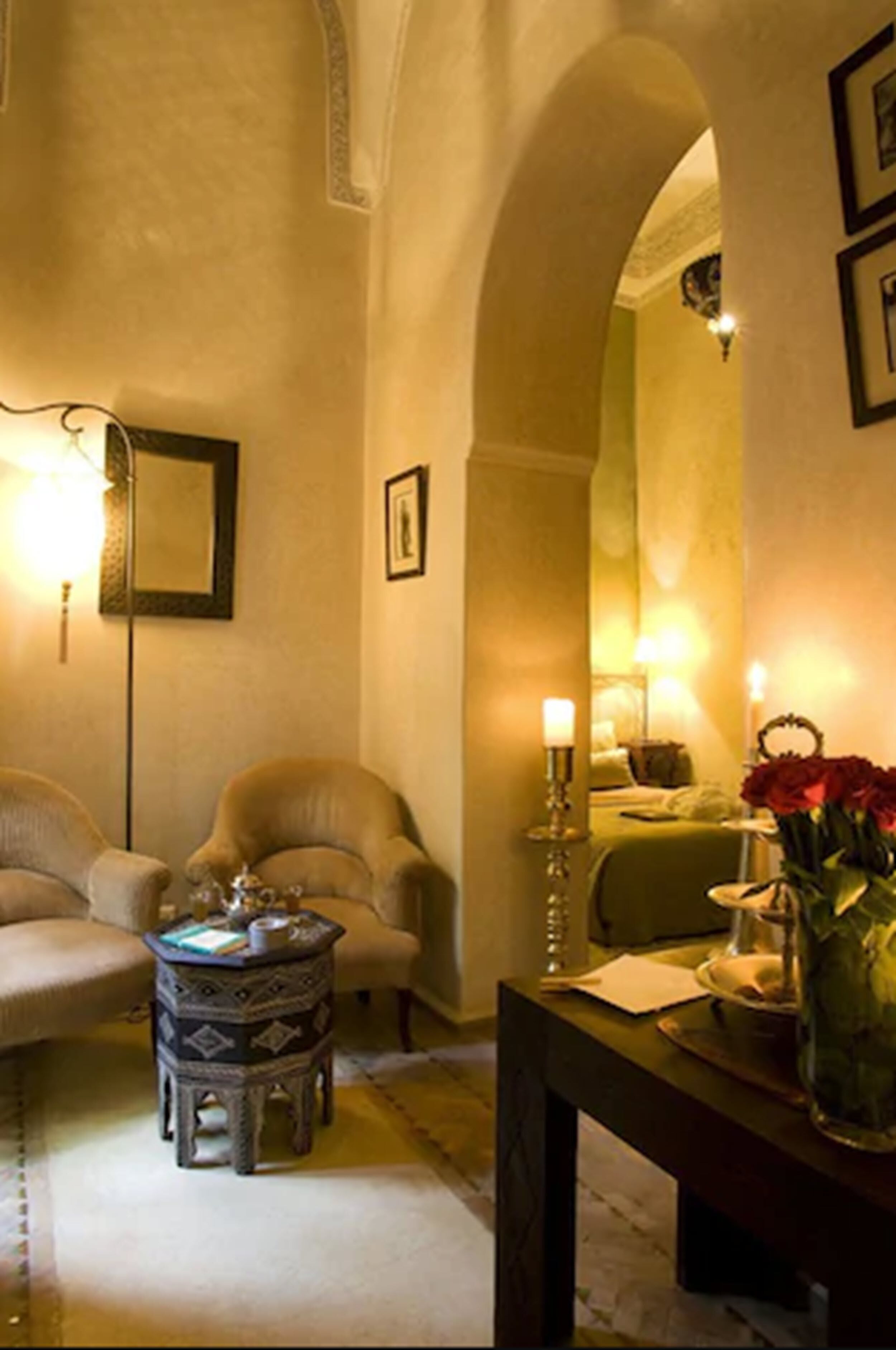 A cozy living room with a sofa, armchairs, a small round table, and a vase with flowers.