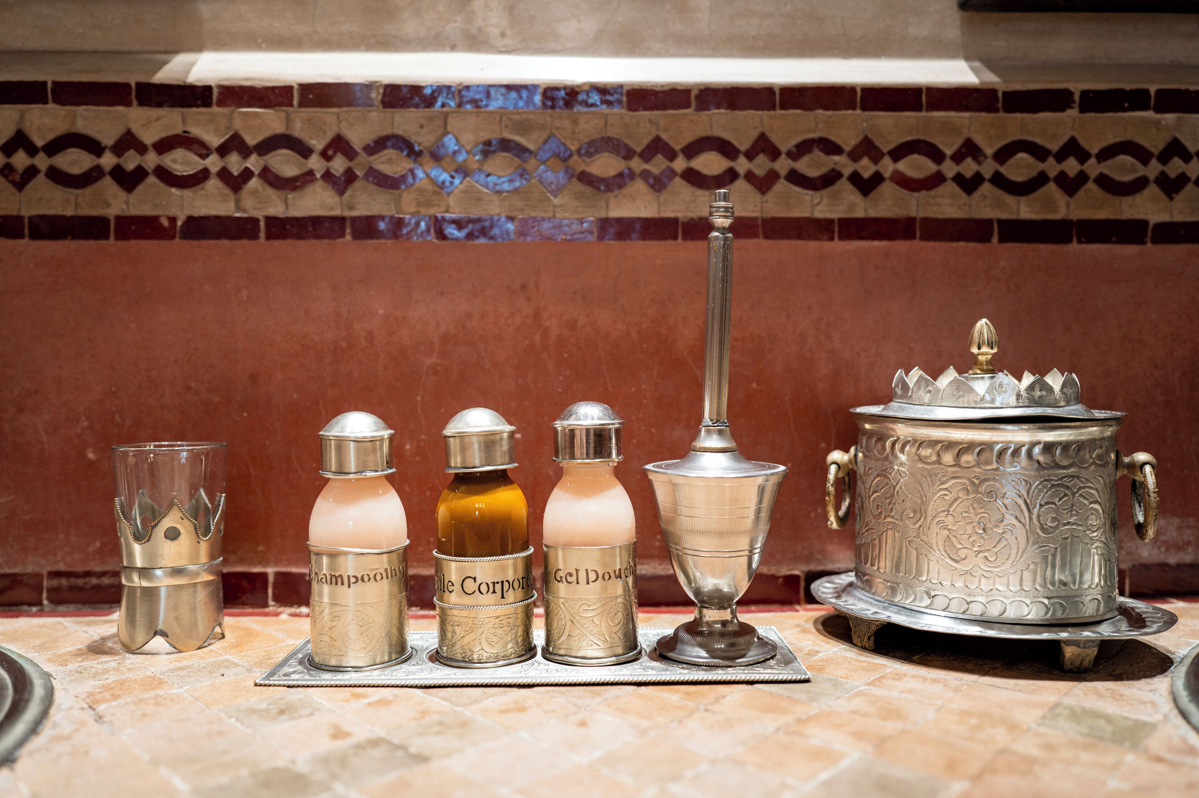 A set of metallic containers labeled with various toiletries on a tiled surface.