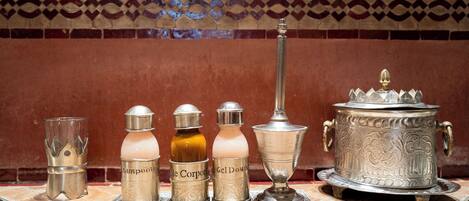 A set of metallic containers labeled with various toiletries on a tiled surface.