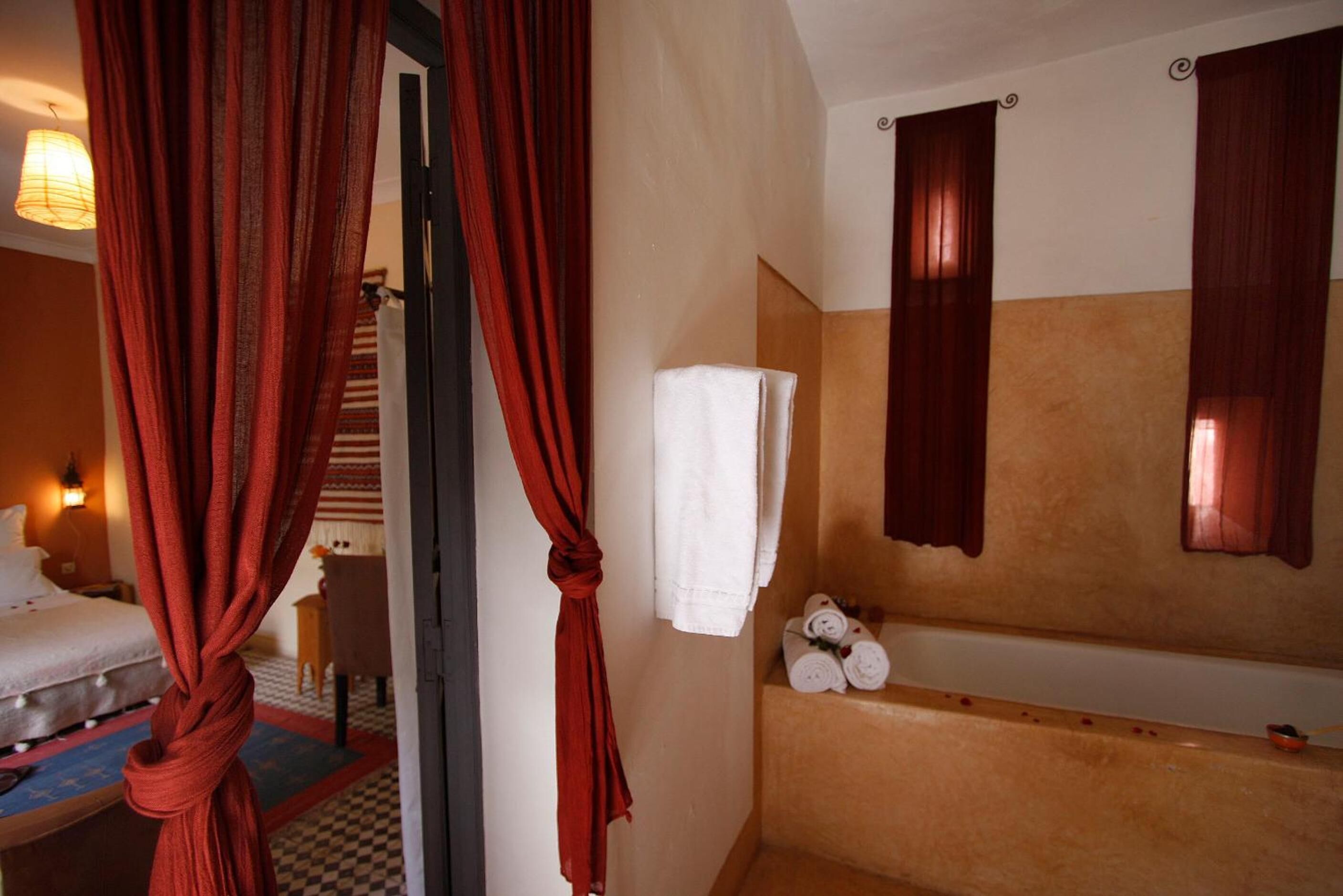 A hotel room with a bed, a bathroom with a bathtub, and a towel rack.