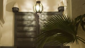 A traditional Moroccan interior with a wooden door, a hanging lantern, and a patterned wall. - Dar Touyir (Marrakech)