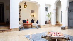 A spacious courtyard with a fountain, seating area, and a door leading to another room. - Dar Touyir (Marrakech)