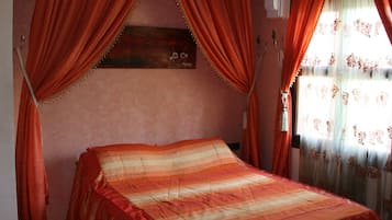 Un dormitorio con cama, cortinas rojas y cabecero de madera con placa.