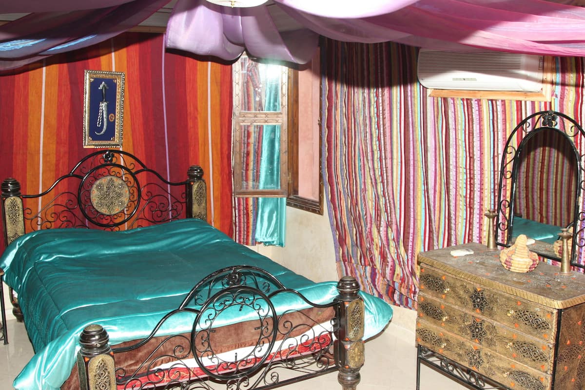 Una habitación con cama, cómoda, espejo y cortinas.