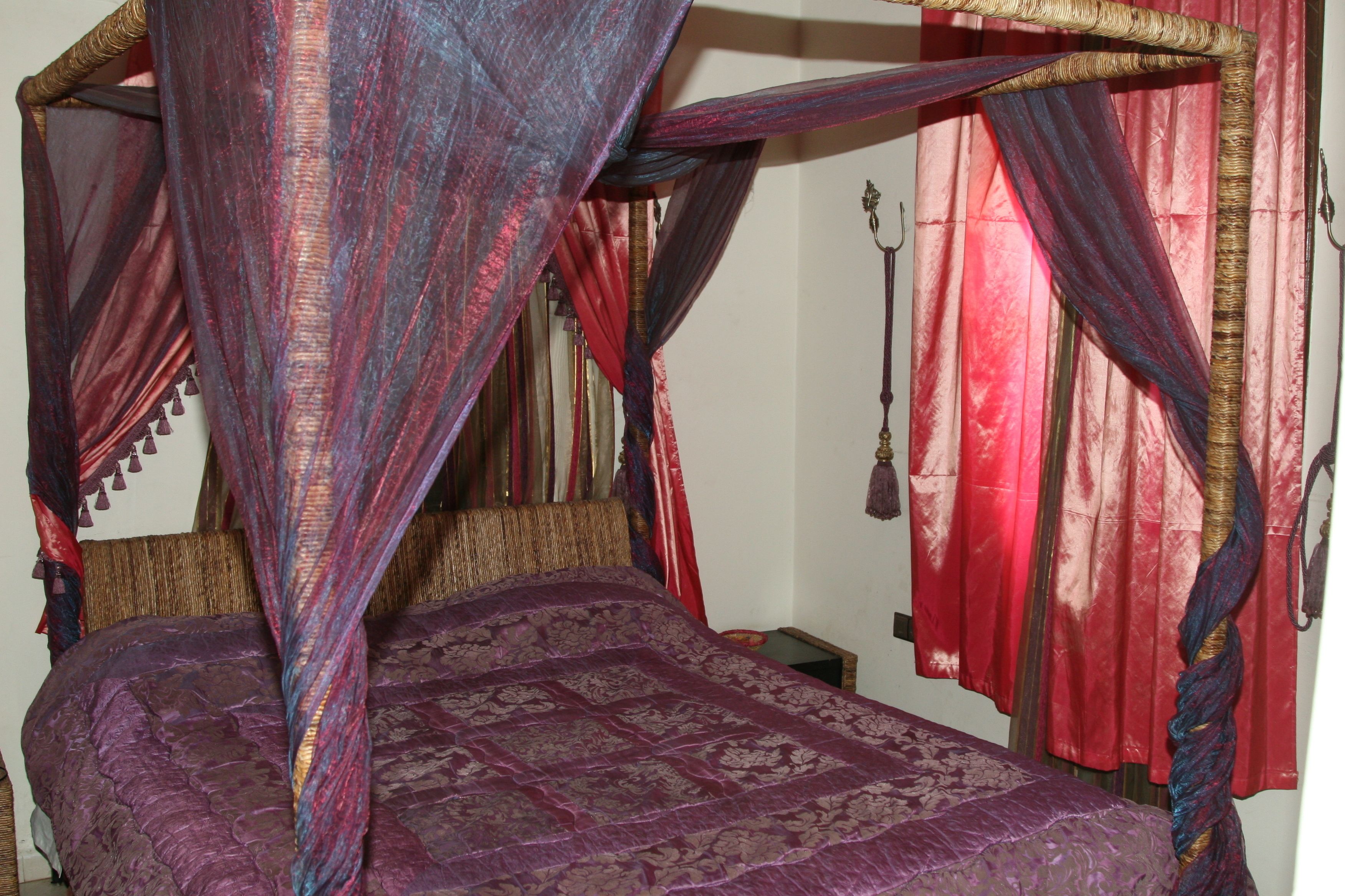 A bed with a canopy, a nightstand, and a hanging lamp.