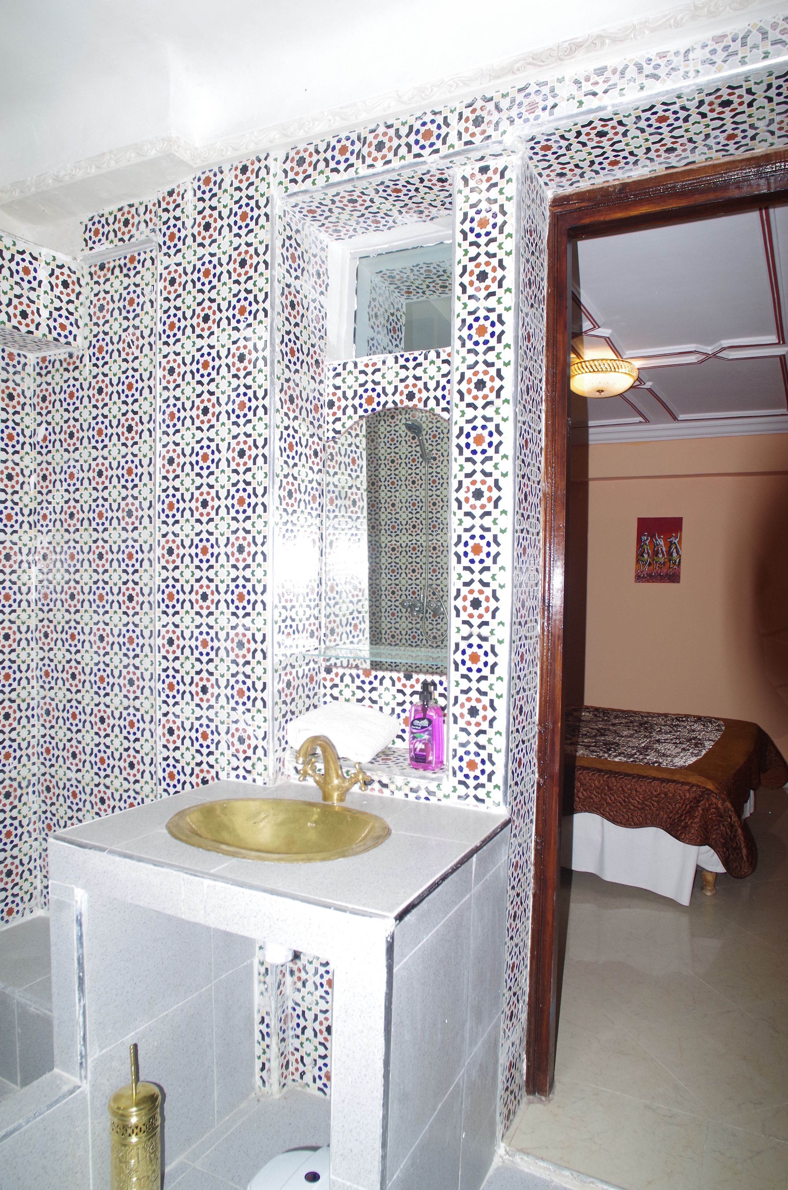A bathroom with a tiled sink, a mirror, and a toilet.