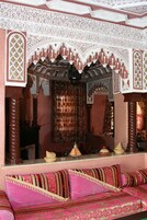 Una habitación de diseño tradicional, con un sofá y cojines estampados, un espejo decorativo y detalles ornamentales en las paredes.