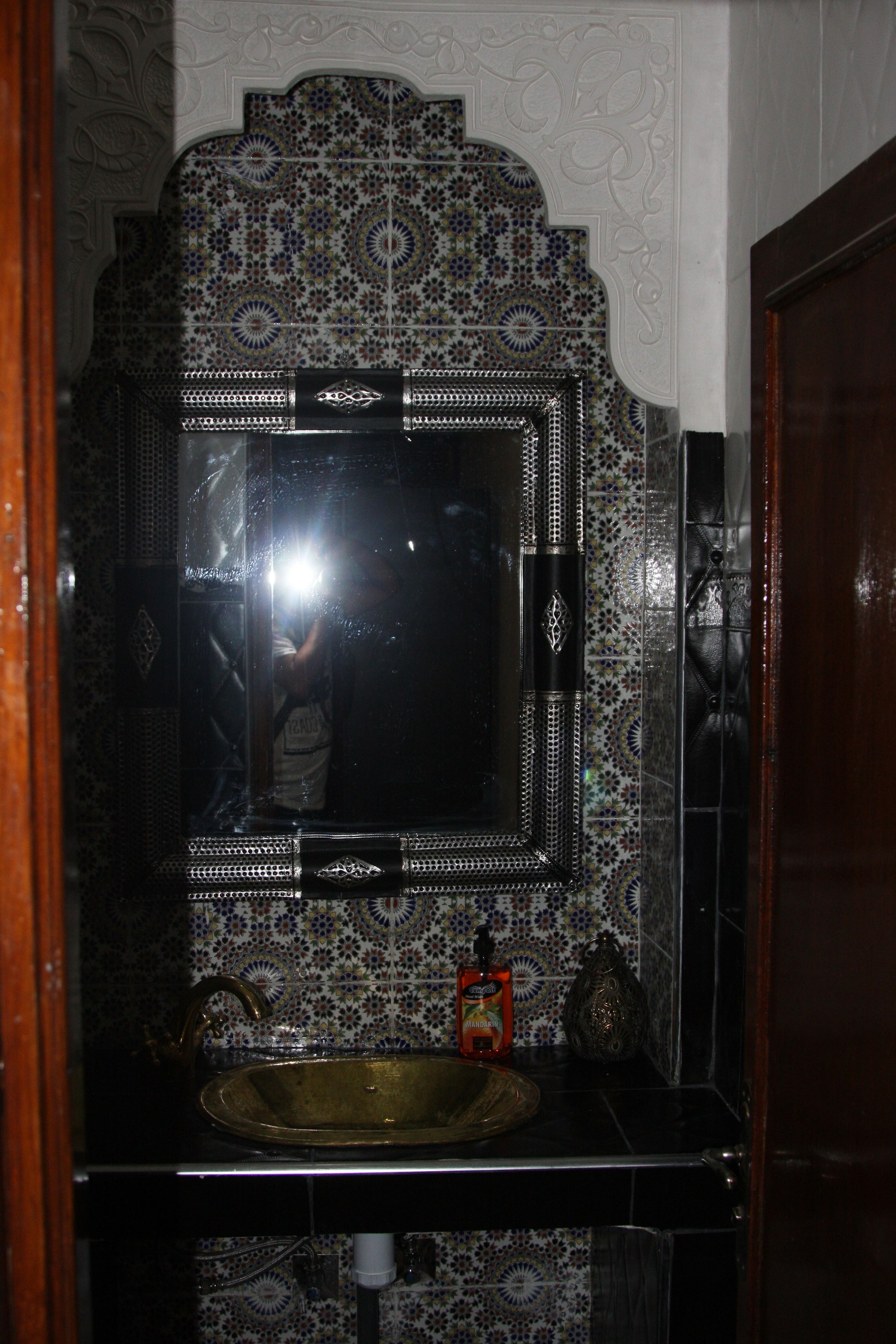 A bathroom with a decorative tiled backsplash, a sink, and a mirror.