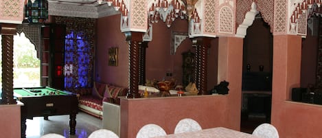Una habitación con mesa de billar, sofá y comedor con mesa y sillas.