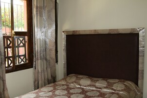 A bedroom with a bed, a window with a view, and curtains.