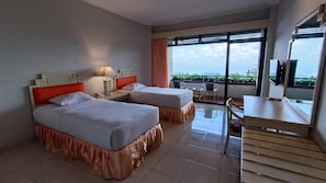 Camera d'albergo con due letti, una scrivania, una sedia e un balcone con vista.