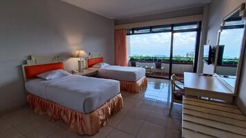 Habitación de hotel con dos camas, un escritorio, una silla y un balcón con vistas.