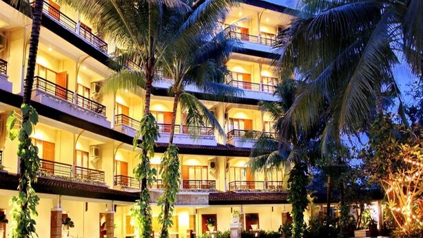 A multi-story hotel with balconies, a swimming pool, and palm trees. - Le Dian Hotel (BANTEN)