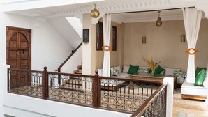 Un vaste espace de vie comprenant un escalier, un ensemble de canapés et un vase décoratif.