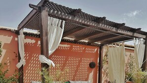 Une terrasse sur le toit agrémentée d’une pergola en bois, de sièges d’extérieur et de plantes en pot.