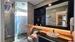 Een moderne badkamer met een douchecabine van glas, een toilet, een wastafelmeubel met een wastafel en een grote spiegel.