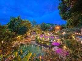 Un resort con piscina, mobiliario exterior y abundante vegetación.