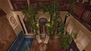 Un patio interior con piscina, dos sillas y plantas en macetas.