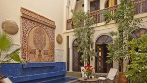 Un patio con piscina, sillones de descanso y suelo de baldosas.