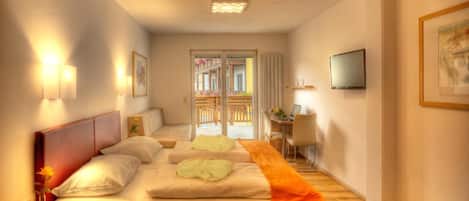 Habitación de hotel con cama, mesita de noche, lámpara y televisión en la pared.