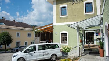 A white van parked in front of a building with a sign that reads 'First Hotel.'