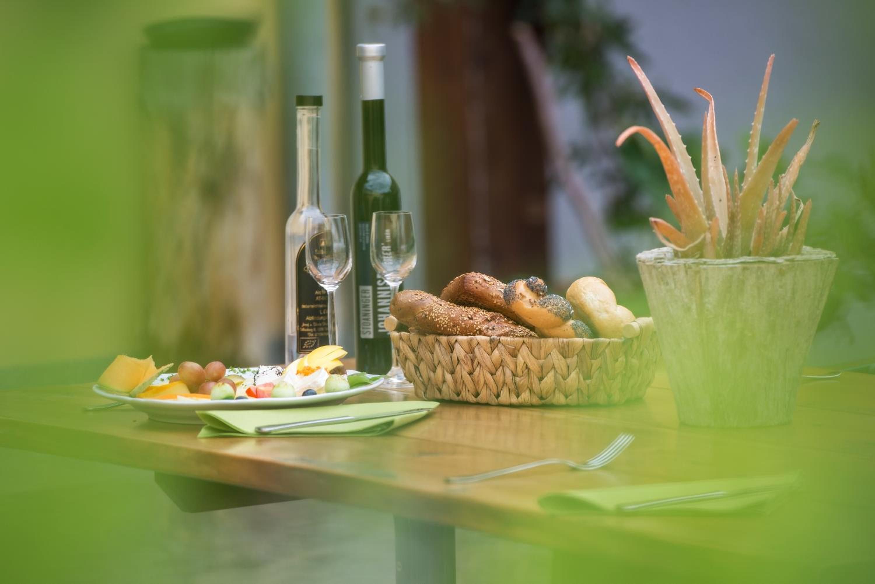 Una mesa con un plato de comida, un cesto de pan, una copa de vino y una botella de agua.