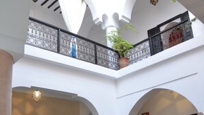 An indoor courtyard with arches, a balcony with a railing, and seating areas. - Riad Ailen (Marrakech)