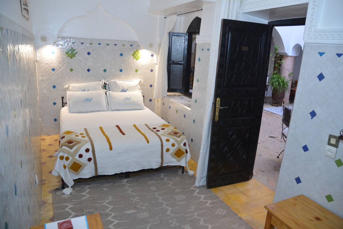Un dormitorio con una cama, una mesita de noche y una puerta que da a un patio.