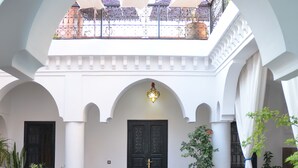 A courtyard with arches, a balcony, and potted plants. - Riad Ailen (Marrakech)