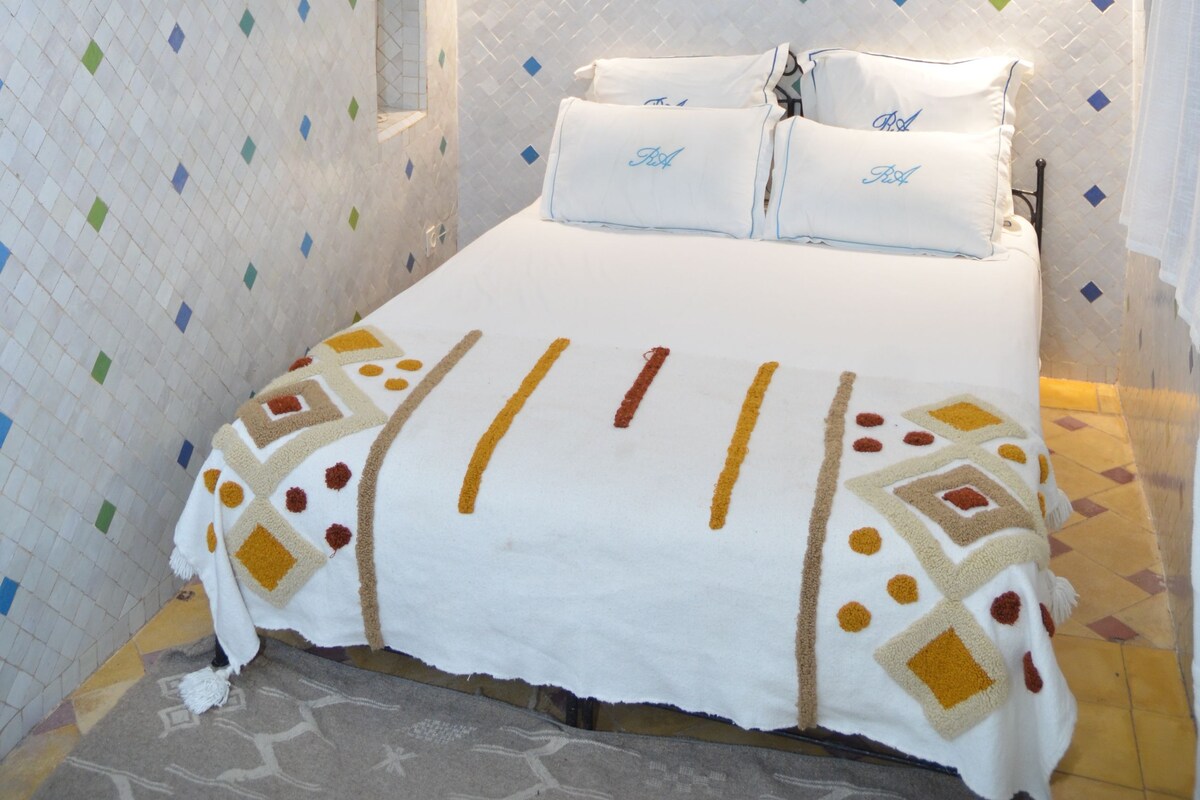 Un dormitori amb un llit, aire condicionat fixat a la paret, una làmpada decorativa i una paret amb un disseny.