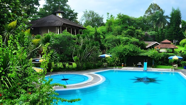 A swimming pool surrounded by lush greenery and a gazebo. - Taman Sari Hotel Dan Resort (Sukabumi)